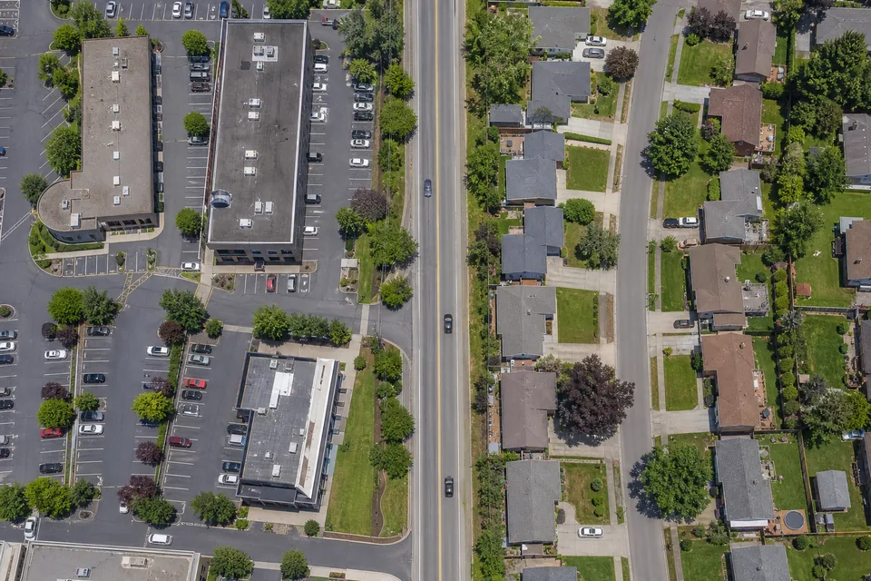 Drone view straight down on an office park on one side of a road and a residential street of family houses on the other