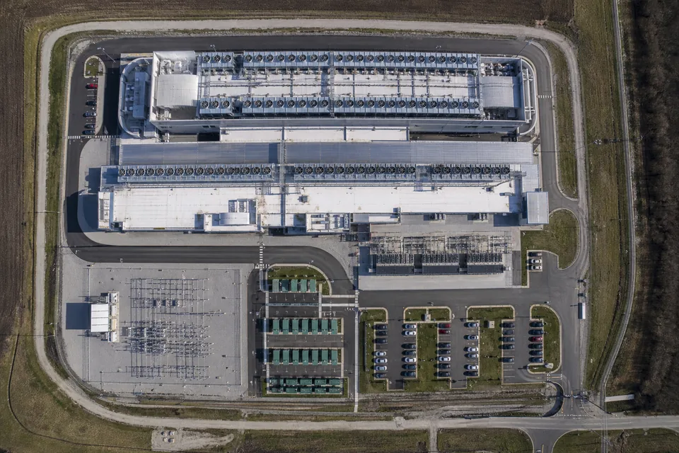 Drone view straight down on a data center campus with rows of rooftop cooling units, a substation and a generator yard